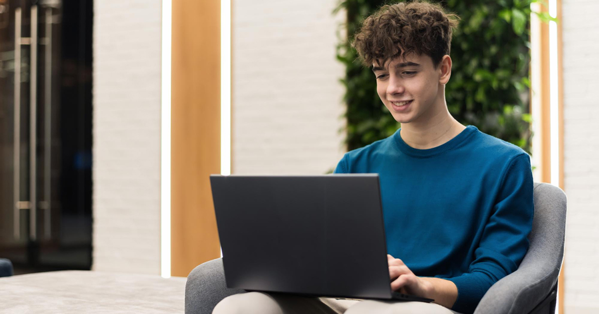 Jeune garçon d’environ 16 ans assis devant un ordinateur portable