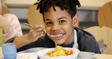 Enfant mangeant dans une cantine scolaire à Cergy