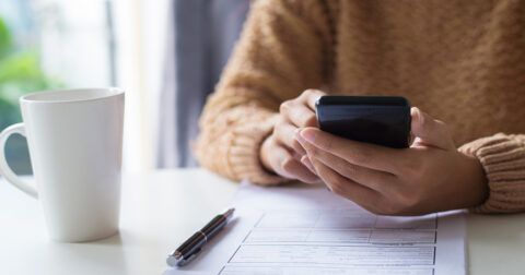 Main sur smartphone et document administratif